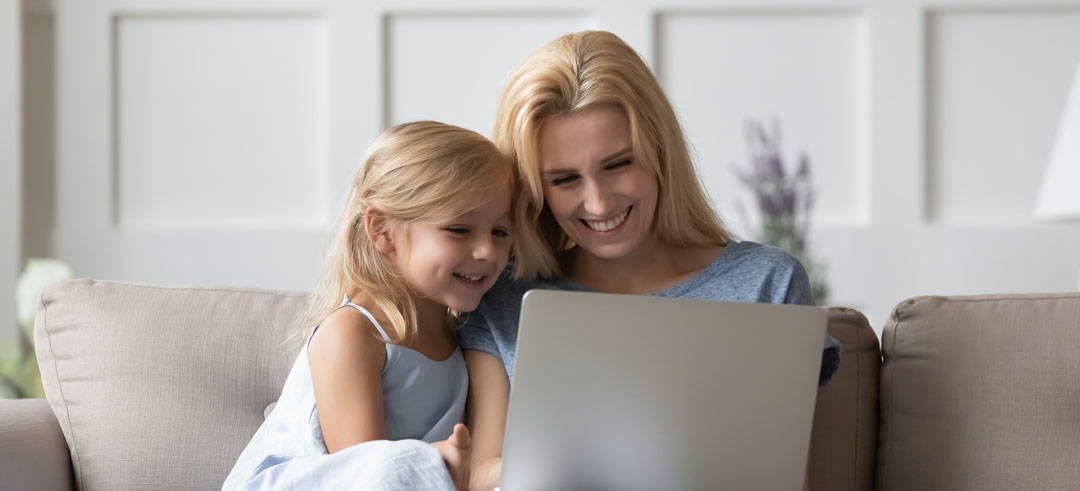 Madre e hija sonriendo mientras visualizan algo en el ordenador