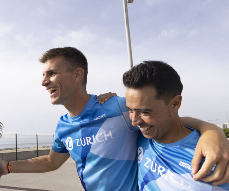 dos colaboradores Zurich abrazados y sonrientes tras correr una carrera