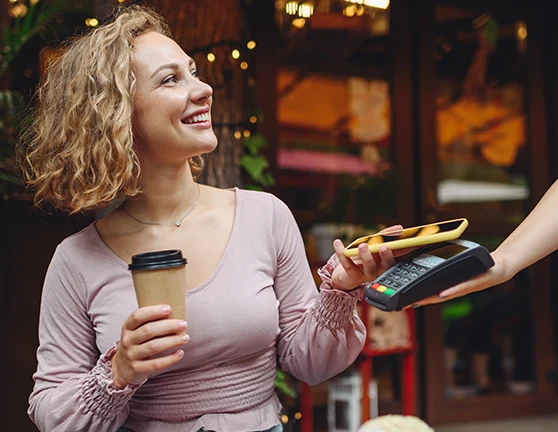 Mujer joven pagando un café con el móvil en un datafono 